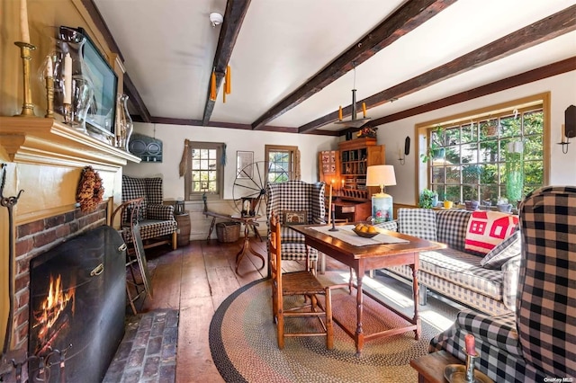 sitting room with a fireplace, plenty of natural light, beamed ceiling, and dark wood-type flooring