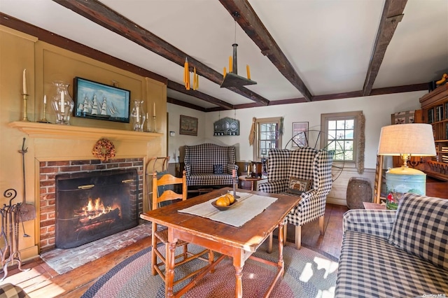 dining area featuring beam ceiling, wood-type flooring, and a fireplace