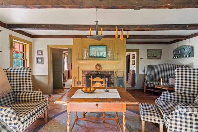 living room with beam ceiling, hardwood / wood-style flooring, and a brick fireplace