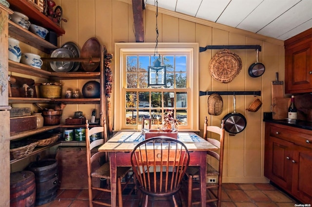 tiled dining space with wooden walls and lofted ceiling