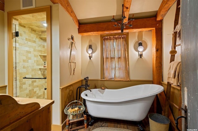 bathroom with beam ceiling and a bathtub