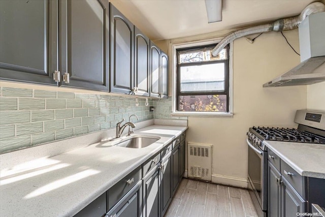 kitchen featuring backsplash, sink, light hardwood / wood-style flooring, extractor fan, and stainless steel range with gas stovetop