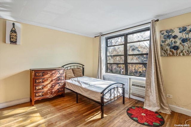 bedroom featuring a wall unit AC, crown molding, and wood-type flooring