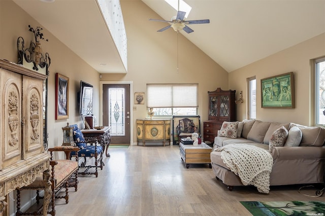 living room with ceiling fan, high vaulted ceiling, and light hardwood / wood-style flooring