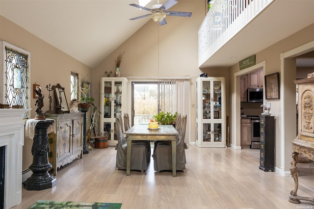 dining room with ceiling fan, high vaulted ceiling, and light hardwood / wood-style flooring