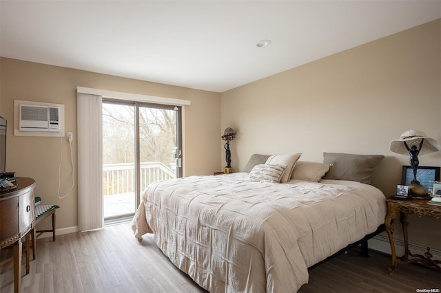 304 S Dunton Ave, East Patchogue, NY 11772 - bedroom with a wall unit AC, access to exterior, multiple windows, and wood finished floors