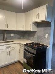 kitchen with white cabinets, sink, dark hardwood / wood-style floors, and black range with gas cooktop