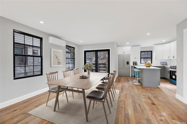 dining space with light hardwood / wood-style floors and a wall unit AC