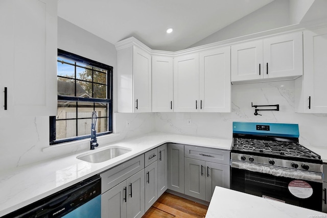 kitchen featuring appliances with stainless steel finishes, backsplash, lofted ceiling, and sink