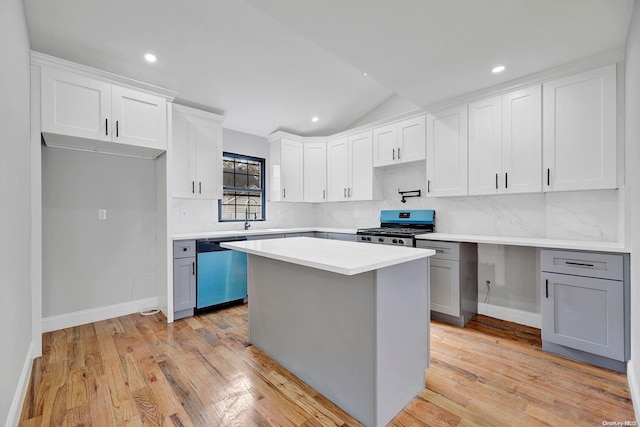 kitchen featuring stainless steel dishwasher, gas stove, light hardwood / wood-style flooring, white cabinets, and a kitchen island