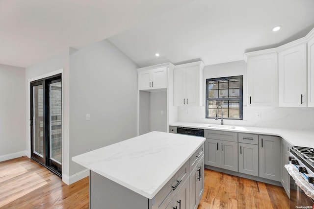 kitchen with gray cabinetry, high end stainless steel range oven, sink, light hardwood / wood-style flooring, and tasteful backsplash