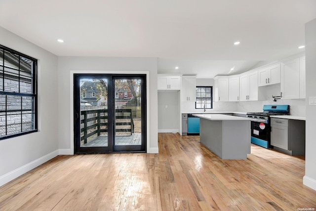 kitchen with white cabinets, a center island, light hardwood / wood-style flooring, and stainless steel range with gas cooktop