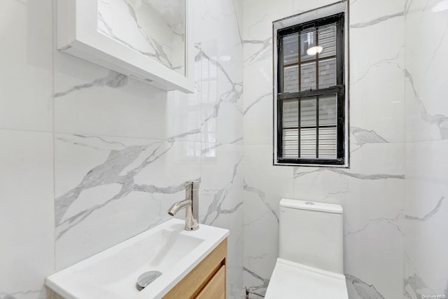 bathroom featuring vanity, toilet, and tile walls