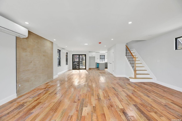 unfurnished living room featuring light wood-type flooring and a wall unit AC