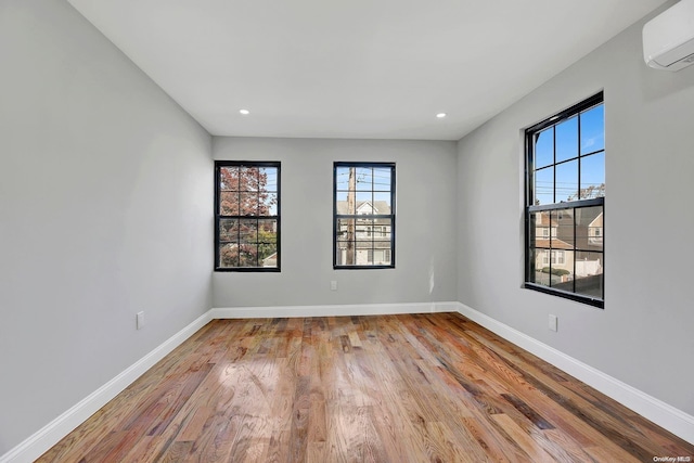 unfurnished room featuring light hardwood / wood-style floors and an AC wall unit