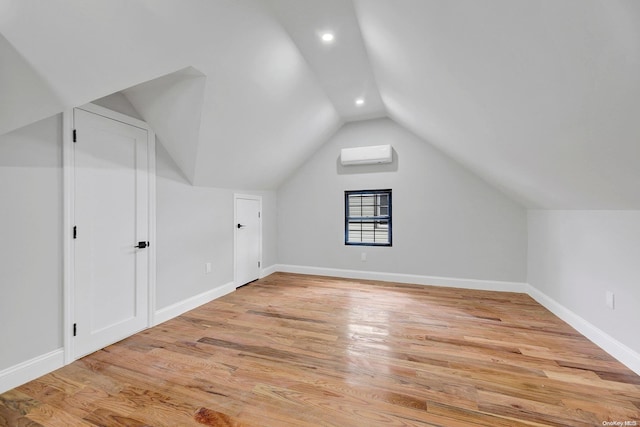 bonus room featuring vaulted ceiling, light hardwood / wood-style flooring, and a wall unit AC