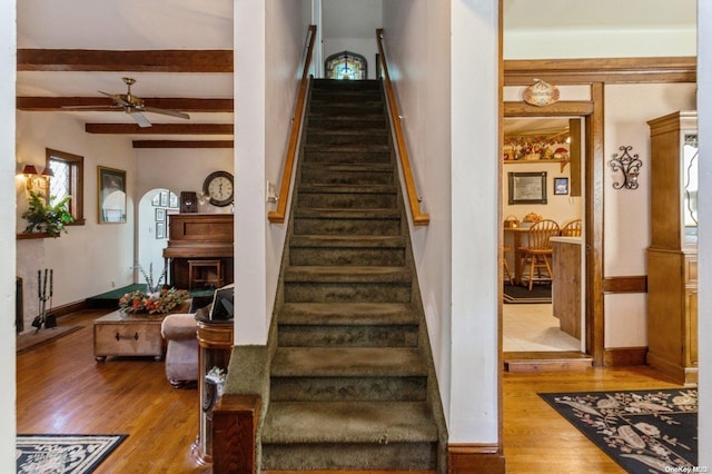 stairs with beamed ceiling, hardwood / wood-style floors, and ceiling fan