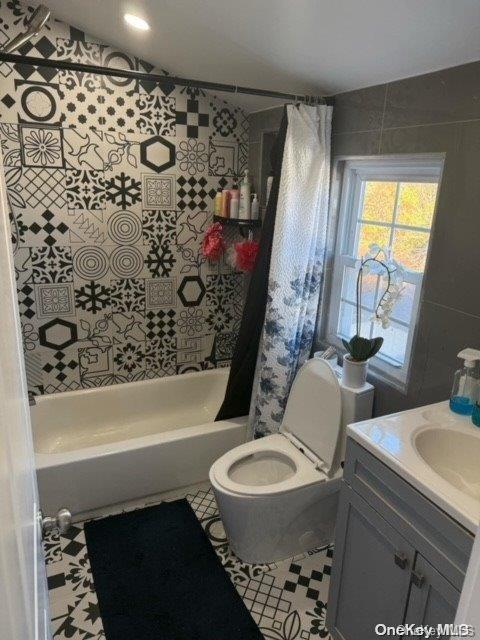 full bathroom featuring tile patterned flooring, vanity, shower / bath combination with curtain, and toilet