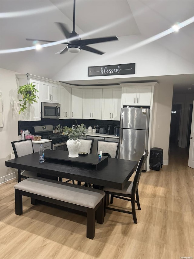 dining space with high vaulted ceiling, light hardwood / wood-style flooring, and ceiling fan