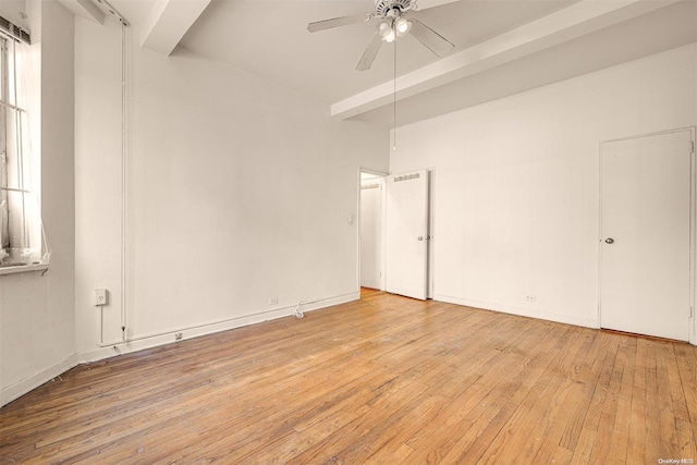 empty room with ceiling fan, beam ceiling, and light hardwood / wood-style flooring