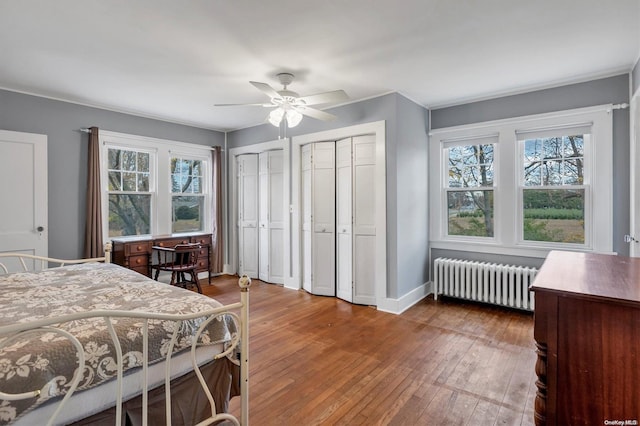 bedroom with hardwood / wood-style flooring, ceiling fan, radiator, and multiple windows