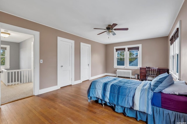 bedroom with multiple windows, hardwood / wood-style flooring, radiator, and ceiling fan