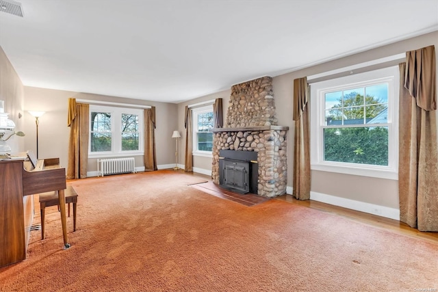 living room with carpet flooring, radiator heating unit, a wood stove, and plenty of natural light