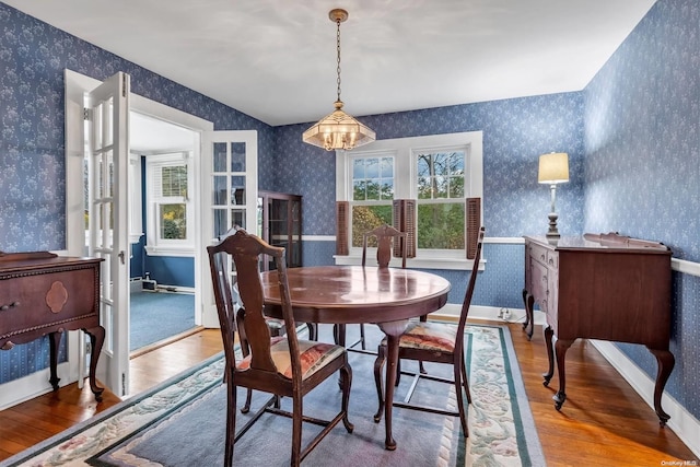 dining space with hardwood / wood-style floors, a chandelier, and french doors