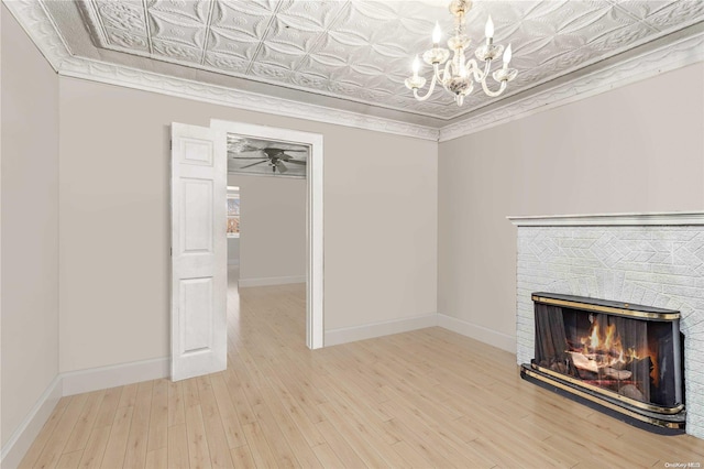 unfurnished living room with a fireplace, ornamental molding, ceiling fan with notable chandelier, and hardwood / wood-style flooring