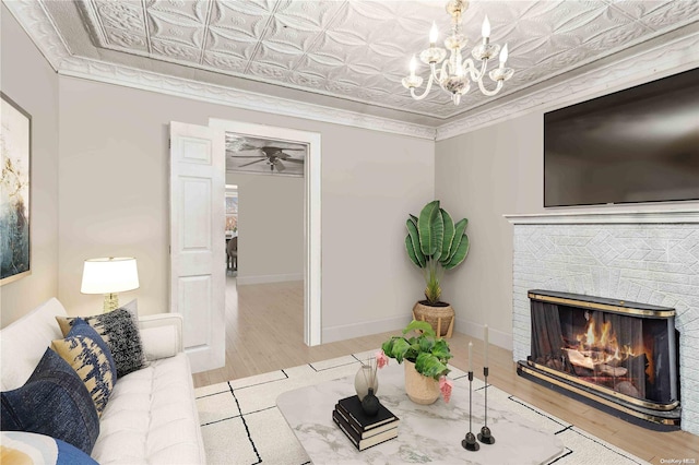 living room with a brick fireplace, light hardwood / wood-style floors, crown molding, and an inviting chandelier