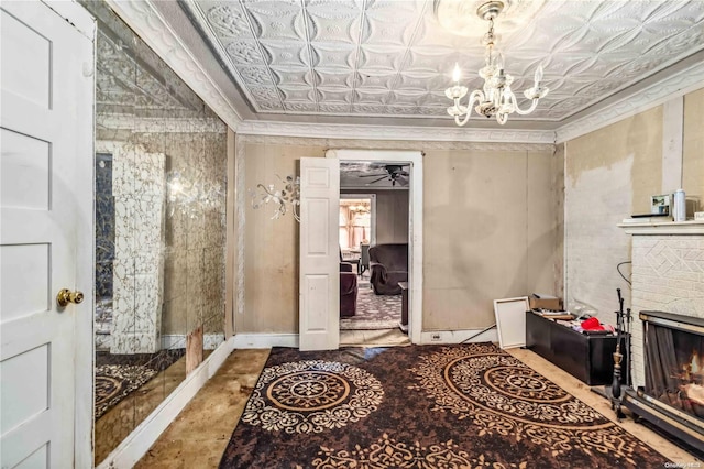 interior space with crown molding, ceiling fan with notable chandelier, and a brick fireplace