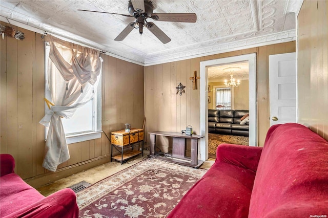 sitting room featuring ceiling fan with notable chandelier and wooden walls