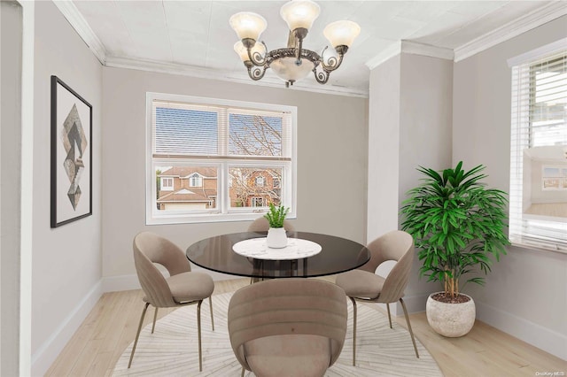 dining area with light hardwood / wood-style floors, crown molding, and a chandelier