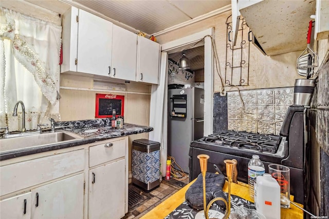 kitchen featuring stainless steel fridge, sink, and white cabinets