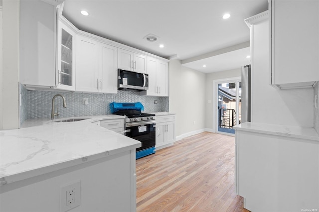 kitchen with appliances with stainless steel finishes, light stone counters, sink, light hardwood / wood-style flooring, and white cabinets