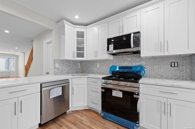 kitchen featuring sink, stainless steel appliances, backsplash, white cabinets, and light wood-type flooring