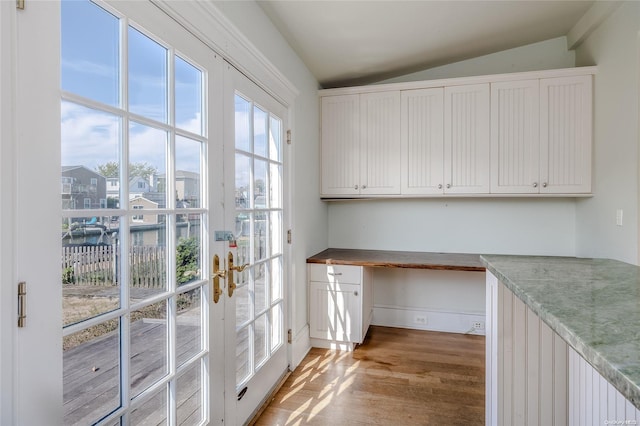 unfurnished office with french doors, built in desk, wood-type flooring, and lofted ceiling