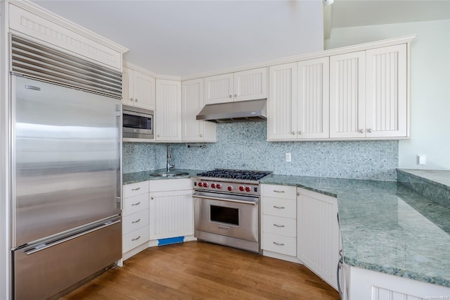 kitchen featuring built in appliances, light hardwood / wood-style floors, white cabinets, and sink