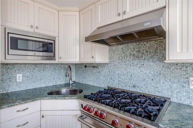 kitchen with decorative backsplash, white cabinetry, sink, and appliances with stainless steel finishes