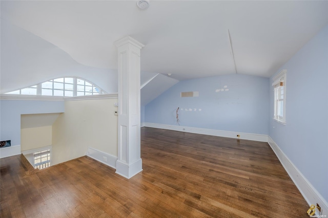 unfurnished living room featuring lofted ceiling, decorative columns, and dark wood-type flooring