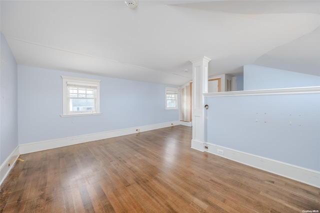 unfurnished room with hardwood / wood-style flooring, plenty of natural light, and vaulted ceiling