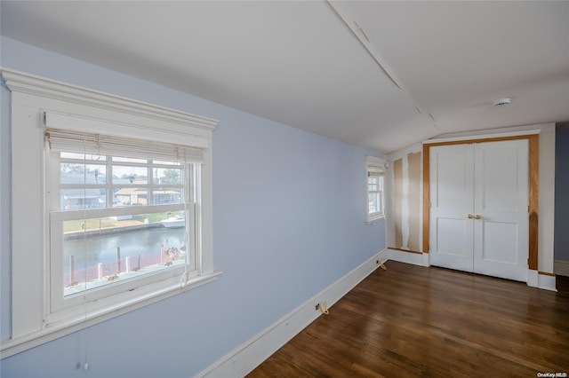 unfurnished bedroom with lofted ceiling, multiple windows, and dark wood-type flooring