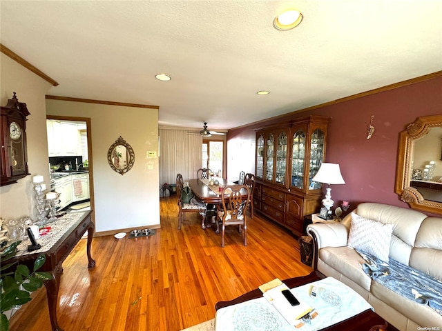 living room featuring wood-type flooring, ceiling fan, and ornamental molding