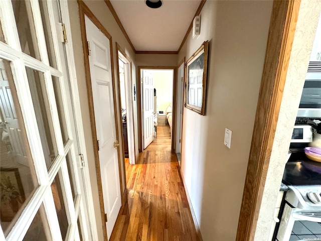 hallway with light hardwood / wood-style flooring and crown molding