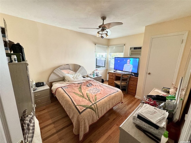 bedroom with hardwood / wood-style floors, a wall mounted AC, and ceiling fan