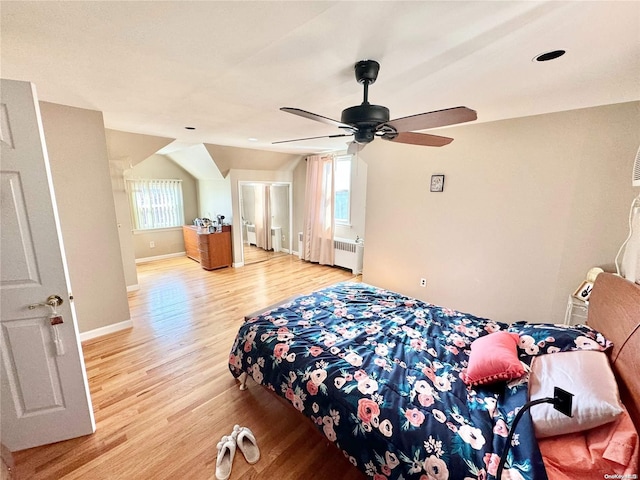 bedroom with ceiling fan, radiator heating unit, light hardwood / wood-style flooring, and multiple windows