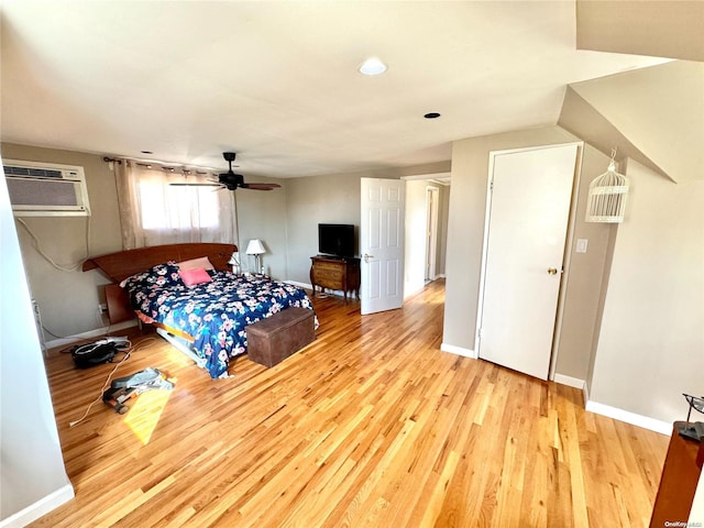 bedroom featuring light wood-type flooring, an AC wall unit, and ceiling fan