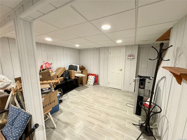 basement with wood walls and a paneled ceiling