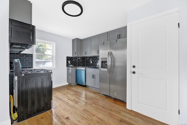 kitchen featuring gray cabinetry, light hardwood / wood-style flooring, stainless steel appliances, and tasteful backsplash