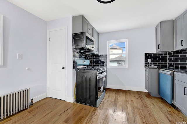 kitchen featuring radiator, gray cabinetry, and appliances with stainless steel finishes